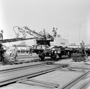 159442 Afbeelding van het beladen van een trein (Robeltrein) met spoorstaven op het terrein van de ...